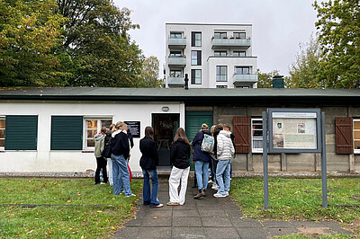 Junge Leute stehen vor der Gedenkstätte Plattenhaus Poppenbüttel