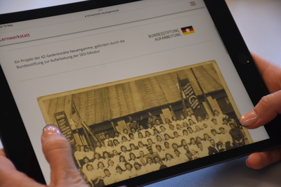 Ein Tablet, das von zwei Händen gehalten wird. Es ist die Seite zu den Bildungsmaterialien aufgerufen.
