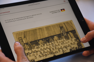 Ein Tablet, das von zwei Händen gehalten wird. Es ist die Seite zu den Bildungsmaterialien aufgerufen.
