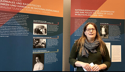 Dr. Susann Lewerenz steht vor 2 Tafeln ihrer Ausstellung "Koloniales und rassistisches Denken und Handeln im Nationalsozialismus"