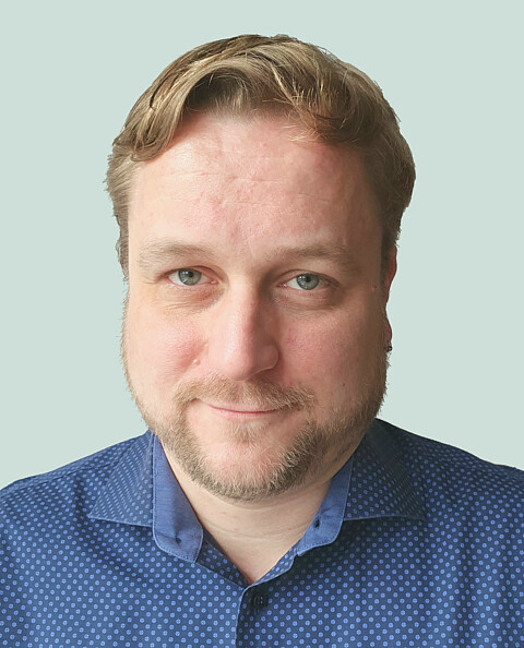 Portraitaufnahme eines Mannes mit blonden Haaren im blauen Hemd