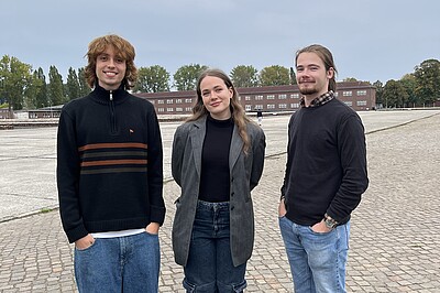 The three volunteers Philipp, Ulyana and Gabriel are standing on the former roll call square at the Neuengamme concentration camp memorial site