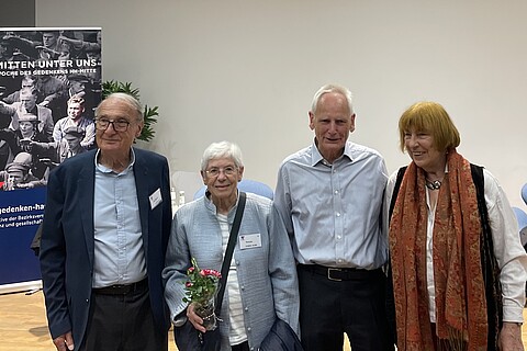 Vor der Veranstaltungsbühne stehen lächelnd Arm in Arm und von links nach rechts Jean-Michel Gaussot, Yvonne Cossu-Alba, Ulrich Gantz und Barbara Brix .