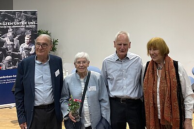 Vor der Veranstaltungsbühne stehen lächelnd Arm in Arm und von links nach rechts Jean-Michel Gaussot, Yvonne Cossu-Alba, Ulrich Gantz und Barbara Brix .