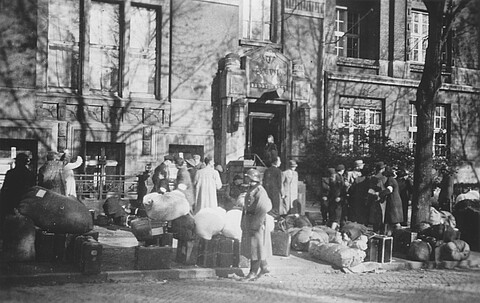Schwarzweißfoto von Menschen, die unter Bewachung des Reserve-Polizeibataillons 101 am Logengebäude ankommen