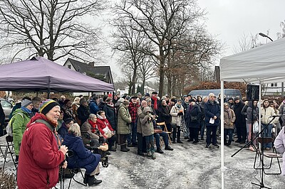 Eine große Menschenansammlung steht am Gedenkstein für das KZ-Außenlager Sasel.