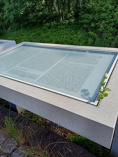 Gedenktafel mit Namen, am Rand liegt eine Rose