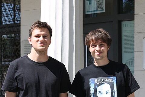 Hajo Eick (links) und Philipp Kremer stehen vor der Millerntorwache - einem Gebäude aus weißem Stein mit Säulen vor dem Eingang