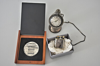 drei Objekte aus dem Nachlass Zegers: Ein Feuerzeug, eine Taschenuhr, eine Medaille