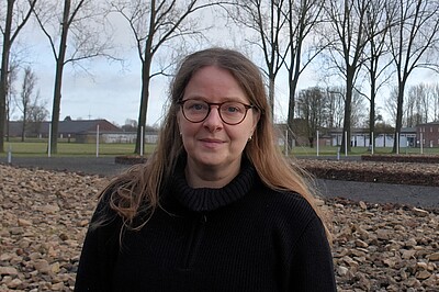 Susann Lewerenz hat lange Haare und trägt eine Brille. Im Hintergrund Bäume.