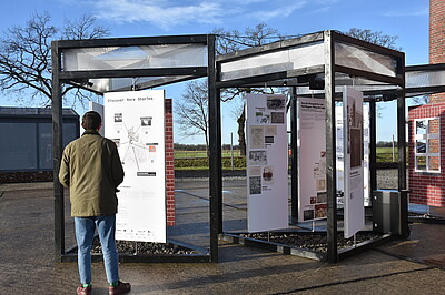 [Translate to English:] Drei Dreiecke mit Ausstellungstafeln, davor Personen
