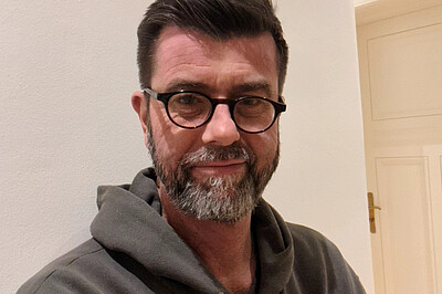 Portrait von Jaromir Balzar. Er trägt eine Brille und einen Kapuzenpullover.