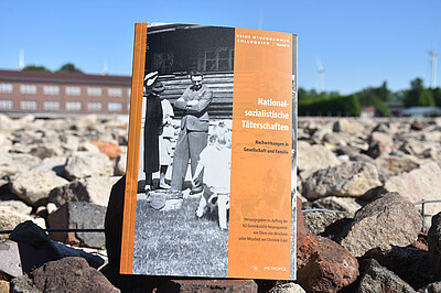Das Buch "Nationalsozialistische Täterschaften" liegt auf Steinen in der KZ-Gedenkstätte Neuengamme