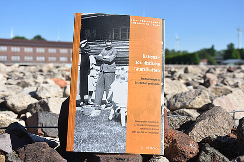 Das Buch "Nationalsozialistische Täterschaften" liegt auf Steinen in der KZ-Gedenkstätte Neuengamme