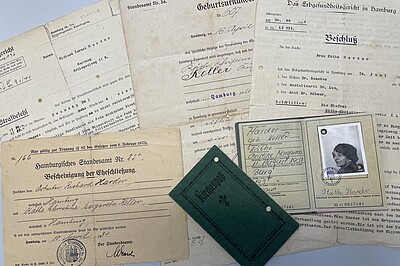 Auf einem Tisch liegen Beispieldokumente aus dem Nachlass, darunter die Bescheinigung der Eheschließung von Käthe und Richard Harder, ein Ausweis und eine Geburtsurkunde von Käthe Harder, ein Strafbefehl gegen Richard Harder und ein Beschluss vom Erbgesundheitsgericht