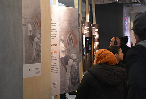 Blick in die Ausstellung "Rechte Gewalt in Hamburg nach 1945" im St. Pauli Museum. Verschiedene Personen, zum Teil mit Kopfhörer, sehen sich Tafeln mit Bildern und Texten an.